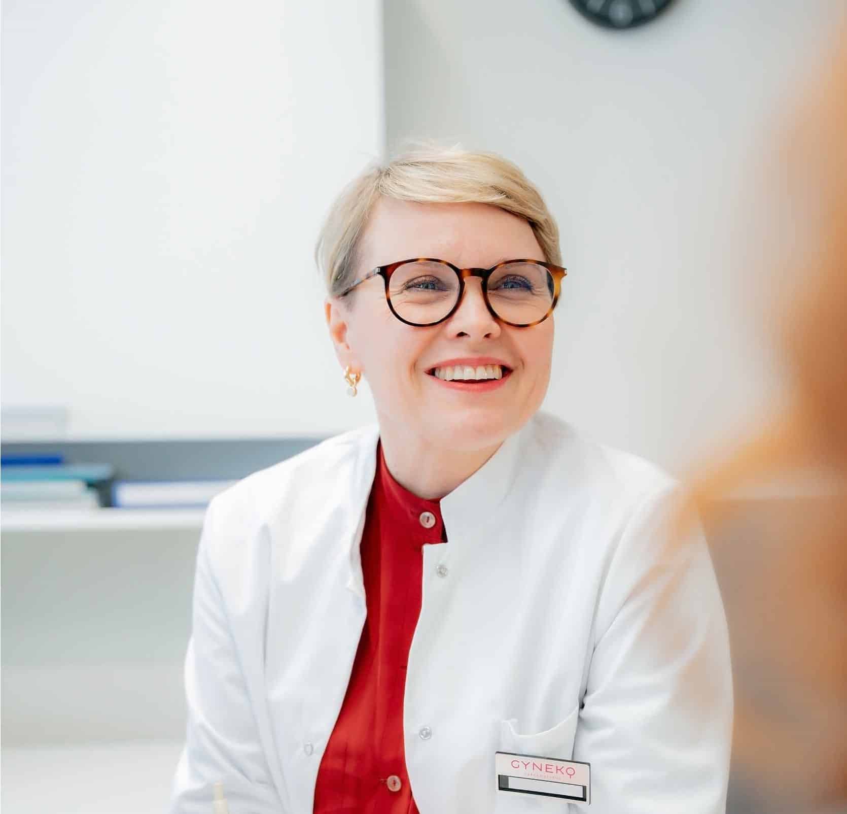 Lääkäri hymyilee potilaalle vastaanotolla Gynekossa Oulussa ja luo ystävällisen ja luottamuksellisen ilmapiirin.